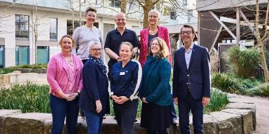 
		Ein Vereinbarkeitslotse schiebt einen Senior im Rollstuhl und dieser lacht und wirft die Arme in die Höhe
	