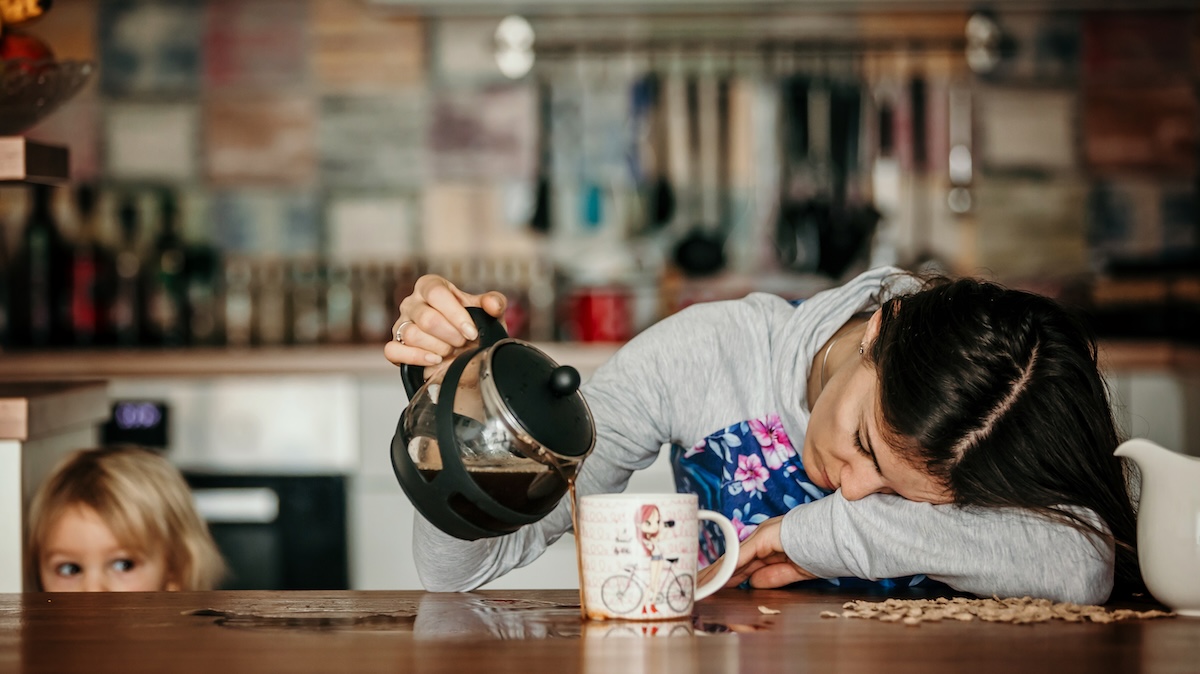 Müde Frau mit Kopf auf Tisch gießt Kaffee in die Kanne